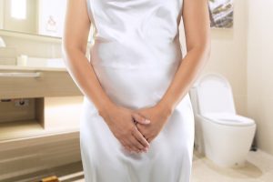 Women in a white dress want to urinating at the toilet. Peeing or urinary pain.