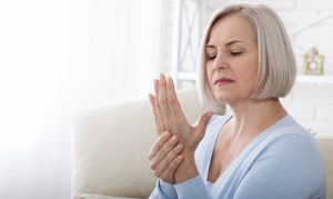 Woman massaging her arthritic hand and wrist closeup