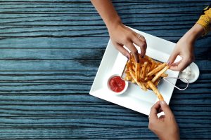 Three Friends Eating French Potato Fries, Serve on Metal Mesh Flying Sieve with Two Dipping Sauce. Lay on Wooden Table. High Angle Top View Shot