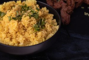 Yellow cooked millet, served in black bowl