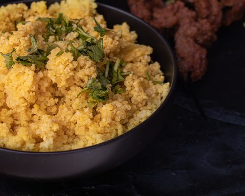 Yellow cooked millet, served in black bowl