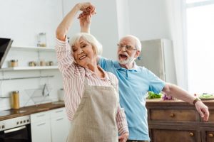 Selective focus of smiling senior couple dancing in kitchen