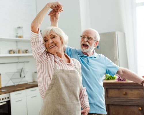 Selective focus of smiling senior couple dancing in kitchen