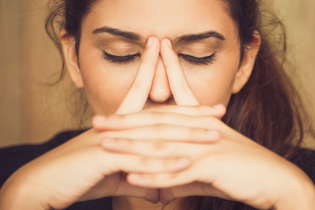 Close-up of face of tired young Caucasian woman rubbing nose. Businesswoman suffering stress or depression