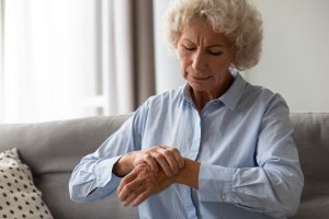 Unhappy senior old hoary woman touching wrist joint, suffering from injured hand. Frustrated stressed middle aged mature female retiree having painful feelings in bones, arthritis osteoporosis concept