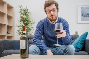 Portrait of man with alcohol drink sitting on sofa at home