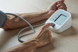 A male person taking self measurement of blood pressure at home with pressure cuff around the arm
