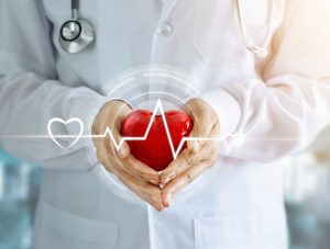 Doctor with stethoscope and red heart shape with icon heartbeat in hands on hospital background