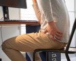 Japanese male businessman who suffers back pain from working from home
