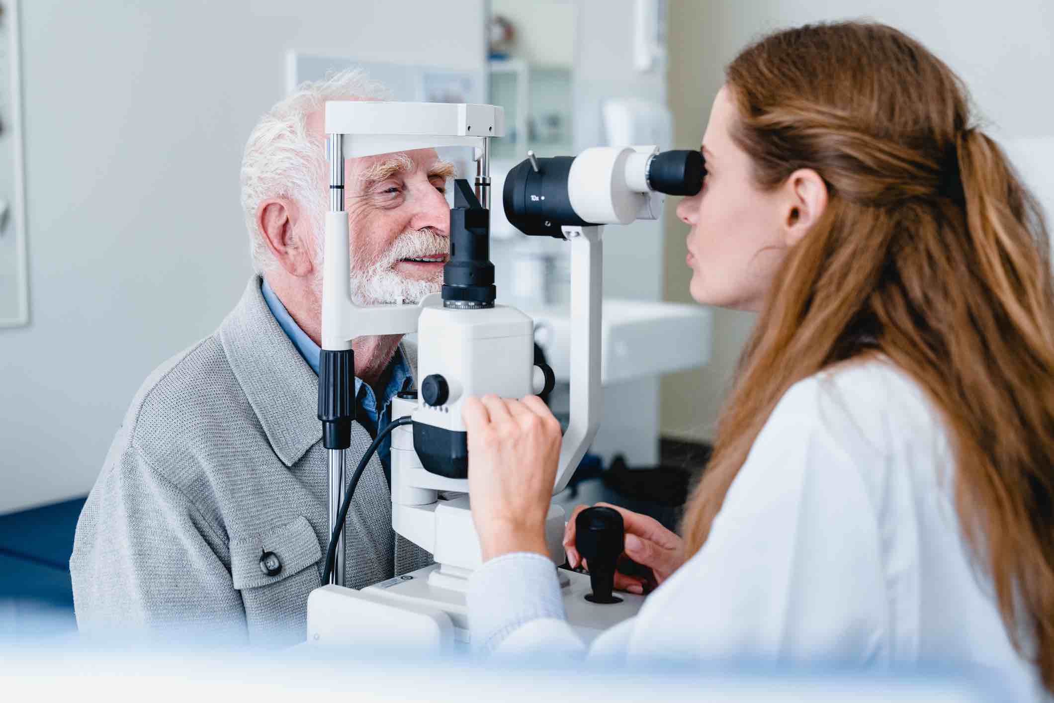 Female ophthalmic doctor diagnosing elderly patient`s sight using ophthalmic equipment