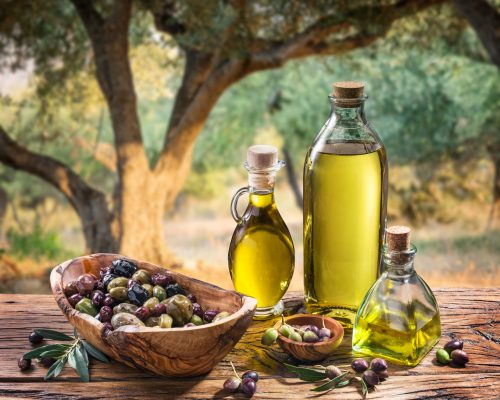 Olives and olive oil in a bottle on the background of the evening olive grove.