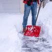 Man shoveling snow in the driveway with a red snow shovel