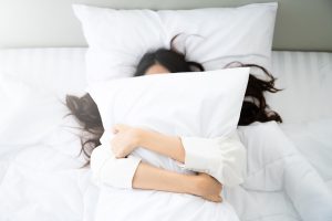 Happy asian young woman hug pillow in bed in the morning