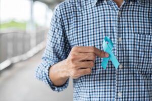 Mes de Concientización sobre el Cáncer de Próstata en noviembre, un hombre con una camiseta azul con la mano sosteniendo una cinta azul en apoyo de las personas vivas y enfermas.  cuidado de la salud, hombres internacionales, padre y concepto del día mundial del cáncer