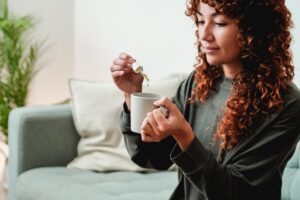 Cuentagotas de aceite de cbd - Mujer joven que toma aceite de cannabis en bebida de té para el tratamiento de la ansiedad y el estrés - Medicina alternativa