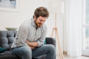 Guy feeling unwell with a stomach ache while sitting at home