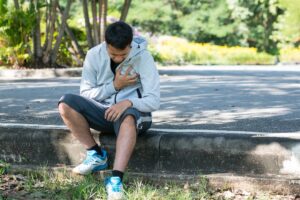 Asian sportsman with chest pain sat down after running in the park the injury of exercise concept