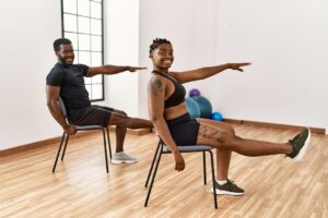 Young african american couple training with chair in sports center.