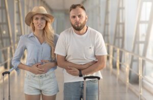 Couple with stomach ache, standing in airport terminal, free space