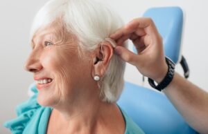 doctor helping senior patient with hearing aid , close-up