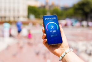 Woman using daily activity tracking app on phone showing 10 000 steps daily goal achievement