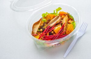Healthy salad in a plastic box with plastic fork. Ready to eat healthy food on white background