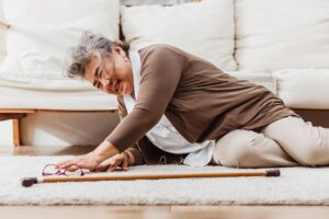 Asian senior woman falling down lying on floor at home alone. Elderly woman pain and hurt from osteoporosis sickness or heart attack. Old adult life insurance with health care and treatment concept