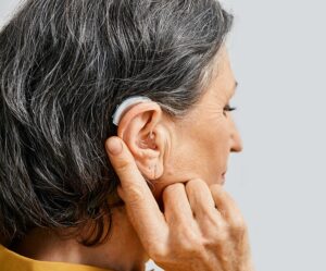 Hearing aid behind the ear of senior woman, close-up
