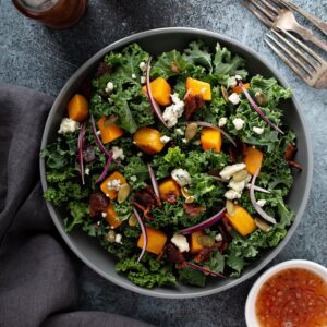 Fall salad with kale and butternut squash, blue cheese and hot bacon dressing