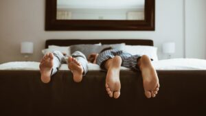 Feet of two people sleeping on bed. People sleeping on bed in different positions.