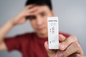 young stressed man holding Coronavirus(Covid-19) positive test result with Antigen Rapid Test kit (ATK)