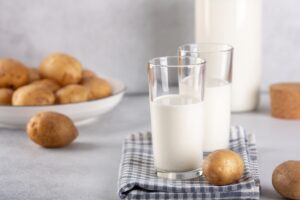 Vegan friendly potato milk in glasses on gray table. Alternative plant based milk and potato tubers - Image