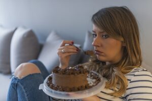 Depressed woman eats cake. Sad unhappy woman eating cake. Sad woman eating sweet cake. Close up of woman eating chocolate cake.food, junk food, cooking, baking and holiday concept
