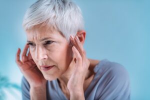 Senior woman suffering from tinnitus or ringing in her ears.