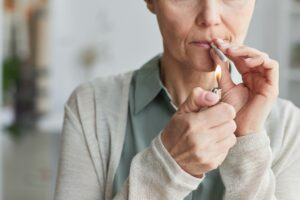 Close up of unrecognizable mature woman lighting cigarette while smoking for medicinal purposes, copy space