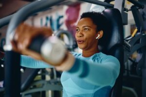 African American athletic woman doing weight exercises for upper body strength during sports training in a gym.