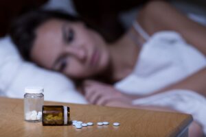 Woman lying in bed, taking sleeping pills