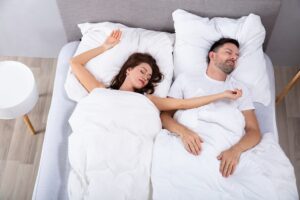 Elevated View Of Married Young Couple Napping On Bed