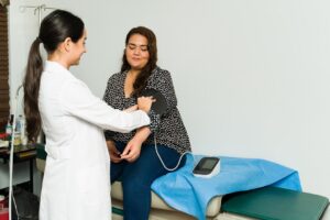 Happy female cardiologist checking the blood pressure of a sick female patient for a medical examination