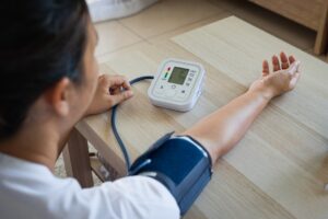 Asian young woman is checking blood pressure and heart rate with digital pressure gauge by herself at home. Health and Medical concept.